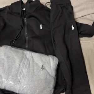 Svart hoodie från Polo Ralph Lauren M - Svart hoodie från Polo Ralph Lauren med dragkedja och snörning i huvan. Klassisk logga broderad på bröstet. Mjuk och bekväm, perfekt för chill dagar. Finns även i grått. Snygg och enkel att matcha med allt.