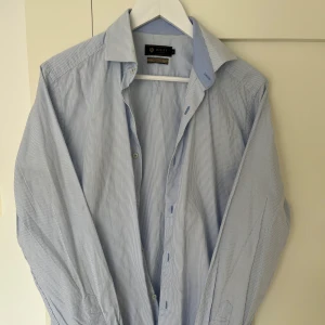 Skjorta från Riley  - Blåvit randig skjorta från Riley i storlek M. Mycket bra skick utan några skador. 