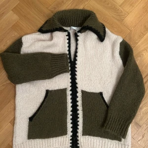 Stickad cardigan jacka i grönt och beige - Säljer en stickad cardigan jacka med dragkedja, stora fickor och kontrastfärgade detaljer. Den är från zara men säljs inte och är väldigt poplär och svår att få tag i!