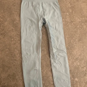 Ljusblå leggings med hög midja - Säljer ett par ljusblå leggings med hög midja och stretchigt material. De är tighta och har en enkel, stilren design utan synliga detaljer. Perfekta för en chill vardagslook eller till träning.
