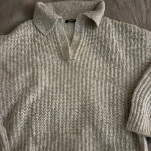 Grå stickad polotröja Gina Tricot - Säljer en grå stickad polotröja från Gina Tricot i storlek XS. Tröjan har en bred krage och v-ringad öppning framtill. Den är ribbstickad och har långa ärmar.
