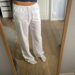 Vita lågmidjade linnebyxor - Säljer ett par vita linnebyxor med avslappnad passform och elastisk midja med snörning. Byxorna har raka ben och sidfickor, perfekta för chill dagar eller strandhäng. Lätta och luftiga i materialet, riktigt sköna att bära. Byxorna är i barn storlek 170 men passar som S/M