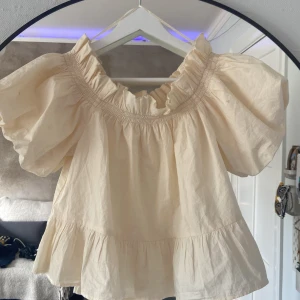 Offshoulder volangblus från Gina Tricot - Supersöt offshoulder blus i ljusbeige från Gina Tricot. Aldrig använd men prislappen är av. Säljer då den aldrig kommer till användning. Köpt för runt 250kr tror jag. Helt nyskick så därav priset.