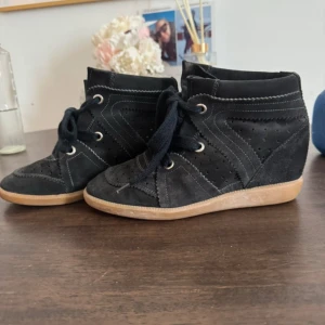 Isabel marant skor - Snygga svarta sneakers i mocka med kilklack och platt gummisula. Skorna har perforerade detaljer, kontrastsömmar och snörning framtill. De är i storlek 38, kan mötas upp i Stockholm🩷