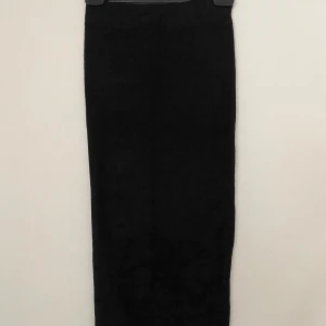 Svart ribbad långkjol Gina Tricot - Svart långkjol från Gina Tricot i ribbad manchester. Kjolen har en rak och slim passform som sitter snyggt längs kroppen. Perfekt för dig som gillar minimalistisk stil och vill ha en enkel men trendig kjol. Snygg att matcha med boots eller sneakers.