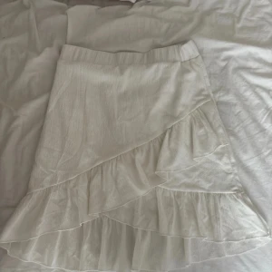 Vit kortkjol med volang - Supersöt vit kortkjol med volangkant och omlott-design. Elastisk midja för skön passform, tveka inte att fråga om bilder/mått osv💗