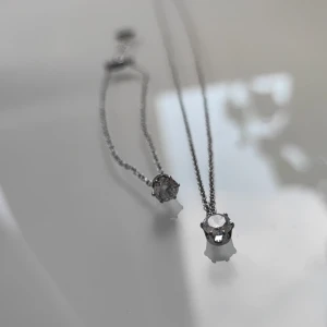 Silverfärgat halsband och armband från Edblad - Snyggt set med halsband och armband från Edblad i silver. Båda har en rund, klar sten som hänger i en tunn kedja och logotypen ingraverad på brickan vid låset. 