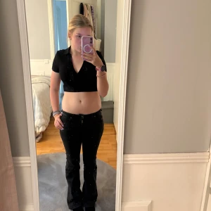 Zara topp - Säljer en svart topp från Zara med korta ärmar och djup v-ringning. Toppen är ribbad och har en krage.