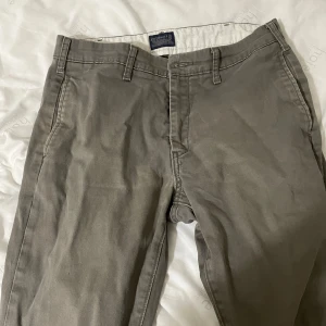 Grå chinos från Levi's W30 L30 - Snygga grå chinos från Levi's med klassisk passform och raka ben. Byxorna har bälteshällor, sidofickor och bakficka med knapp. Tillverkade i mjuk bomull som är skön att bära hela dagen. Perfekta för en clean och avslappnad look.