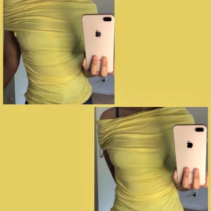 Gul offshoulder topp i stretchigt tyg - Snygg gul offshoulder topp med tight passform och draperad effekt. Tunt, stretchigt material som sitter skönt och markerar figuren. Perfekt för dig som vill sticka ut med en färgglad look.
