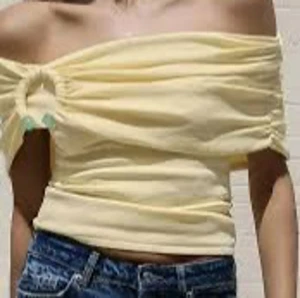 Gul offshoulder tubtopp med ringdetalj - Superfin ljusgul tubtopp med offshoulder och cool ringdetalj med gröna pärlor på ena sidan. Toppen är croppad och har en tight passform som sitter snyggt. Perfekt till jeans eller kjol för en trendig look. Mjukt och stretchigt material. Finns en liten sminkfläck men går knappast att se🤗