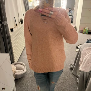 rosa stickad tröja  - Mysig beige stickad tröja från Vila i storlek M. Tröjan har rund halsringning, ribbade muddar och lång ärm. Perfekt för lager-på-lager och enkel att matcha med jeans eller kjol.