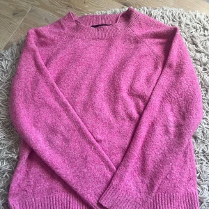 Rosa stickad tröja från Vero Moda - Säljer en rosa stickad tröja från Vero Moda i storlek S. Tröjan har rund hals, ribbade muddar vid ärmslut och nederkant samt långärmad passform. Perfekt för dig som gillar färg och vill ha en mysig och enkel look.