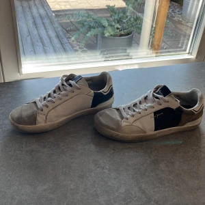 Pepe Jeans sneakers i vitt och blått diskutera pris - Snygga sneakers från Pepe Jeans i vitt med blå och bruna detaljer. Skorna har snörning, rund tå och coolt '1973'-märke bak på hälen. Ovandelen är i skinn och mocka för en schysst mixad look. Perfekta för dig som gillar streetstyle och klassisk design.