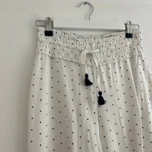 Pyjamasbyxor  - Jättefina vita pyjamasbyxor med marinblå prickar från Kappahl. Byxorna är knappt använda så i fint skick och väldigt mjuka. Byxorna har en lösare passform men med mudd både i midjan och i slutet på benen.
