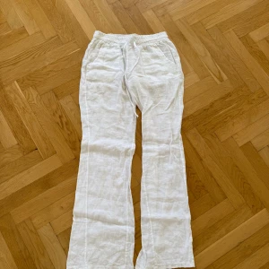 Lågmidjade linnebyxor från Chelsea  - Säljer ett par vita linnebyxor med resår och snörning i midjan. Byxorna har raka ben och två stora fickor framtill. Perfekta för varma dagar och ger en chill och avslappnad look. Sitter bra för både S och M❤️