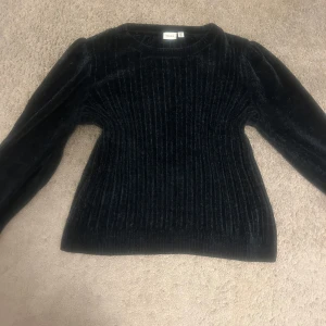 Svart ribbad tröja  - Säljer en svart ribbad tröja från Name It. Tröjan har rund hals, är figurnära och har en snygg struktur som ger extra stilpoäng. Perfekt för dig som gillar en enkel men ändå cool look.