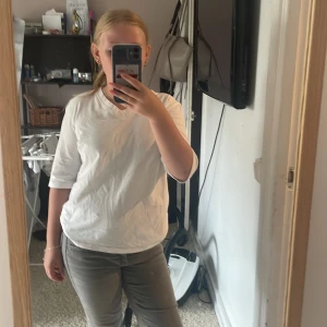 Vit v-ringad t-shirt med trekvartsärm - Enkel och stilren vit t-shirt med v-ringning och trekvartsärm. Modellen är rak och lite loose, perfekt för en avslappnad look. Tillverkad i mjuk bomull som känns skön mot huden. Passar dig som gillar basic men ändå vill ha något med lite edge.