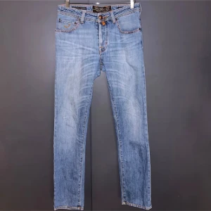 Jacob cohen ljusblå jeans - Snygga ljusblå jeans från Jacob Cohen med rak passform, fem fickor och knäppning med knappar. Jeansen har en riktigt snygg wash och väldigt bra skick på det klassiska märket gjort av päls, bra skick över lag men små slitningar efter användning(skicka privat för mer bilder)