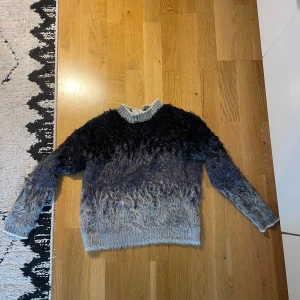 Grå och svart fluffig tröja från Studio Parisien - Mysig fluffig tröja från Studio Parisien i grått och svart. Tröjan har rund halsringning och långa ärmar. Sitter som en storlek S. Jätteskönt material.