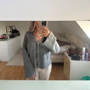 Grå stickad kofta med knappar - Mysig grå stickad kofta med v-ringning från Vila. Den är oversized så även om den är storlek XS så passar den upp till storlek M!! Fin som både tröja och kofta.