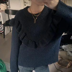 Mörkblå stickad tröja med volang - Säljer en mörkblå stickad tröja med volangdetalj framtill. Tröjan har lång ärm. Tröjan är från ginatricot och är använd ca två gånger! Skriv vid frågor och funderingar!