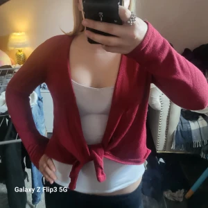 Röd glittrig kofta med knyt - Säljer en röd glittrig kofta med knyt framåfrån , från kappahl (men köpte på secondhand). Koftan har långa ärmar och är tillverkad i ett mjukt, syntetiskt material. Perfekt för att piffa upp en outfit med lite extra färg och glitter.