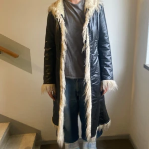 Svart kappa från Miss sixty - Säljer en svart lång (fusk)skinnjacka från Miss sixty med ljus (fusk)päls längs krage, ärmslut och nederkant. Jackan har lång ärm och markerad midja för en snygg fit. Loves it! (Fusk)Meow!