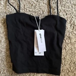 Svart topp från Gina Tricot - Säljer en svart, enkel och stilren linnetopp från Gina Tricot med tunna axelband. Helt oanvänd med lappar kvar. Nypris 99kr. Pris går att diskutera!!!