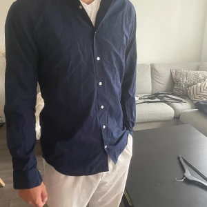 John Henric skjorta - En snygg marinblå skjorta från John Henric som är i ett gott skick.😊 Stl: 39 - M Ny pris 1600 kr vårt pris 229 kr 🤩