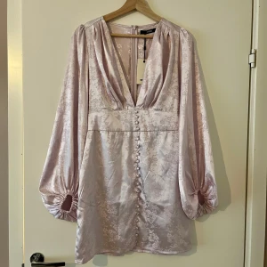 Lila satinklänning  - Kort satinklänning i lila. Helt ny, aldrig använd.