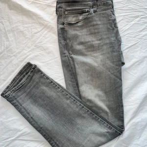 Jack and Jones Jeans - Säljer nu ett par feta grå jeans från Jack and Jones. Dom är i bra skick förutom en lagning vid skrevet men det är bra gjort så att det inte syns👍 Dom är perfekta nu inför sommaren. Dom är i storlek 36x32 och är i slim fit modell. Hör av er vid frågor🤝