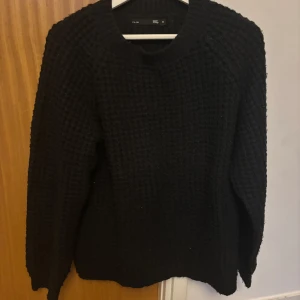 Svart stickad tröja  - Säljer en stilren svart stickad tröja. Tröjan har en klassisk rund hals och långa ärmar, perfekt för kyligare dagar. Den har en texturerad yta som ger en extra dimension till din outfit. Passar bra till både jeans och chinos.