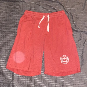 Röda shorts med tryck - Snygga röda shorts med ett tryck på ena benet som säger 'Surfside Beach'.