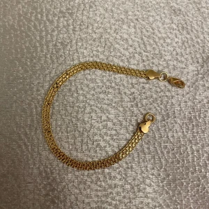 Guldpläterad armband med flätad design - Elegant guldarmband med en fin flätad design. Armbandet har en säker karbinhake som gör det enkelt att ta på och av. Perfekt för att lägga till en touch av lyx till din stil. Rostar ej. Helt ny