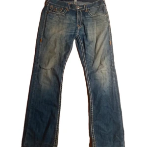 True religion jeans - Feta true religion jeans Ricky super t I storlek 34, har en reva på knät som jag tror är en del av designen. Midja 45cm ytterbens lägnd 110cm, innerben 82cm, ben öppning 24cm, för frågor eller mer bilder! fast pris 