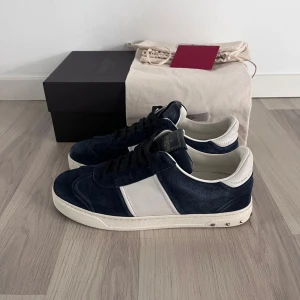Valentino flycrew  - Snygga Valentino sneakers i blå mocka med vita detaljer. Skorna har en klassisk design med snörning och en robust sula med mönster. Perfekta för en stilren look| Hör av dig vid minsta fundering 🤔 