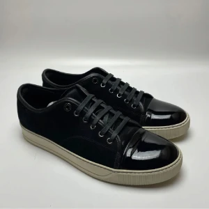 Lanvin Skor Svart - Tjena! Jag säljer mina trendiga Lanvin skor i svart mocka med glansig cap toe. Skorna är i storlek UK10 vilket motsvarar storlek 44. Skorna är i fint skick och har endast lite små repor/crease på tån!✌️