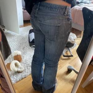 Blå bootcut jeans - Snygga blå bootcut jeans med en klassisk femficksdesign. De har en lågmidjad passform och är perfekta för en avslappnad stil. Jeansen har en lätt tvättad look som ger dem en cool vintagekänsla. !!!!Finns en defekt (sid 3) men går enkelt att sy ihop.