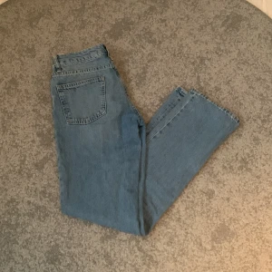 Blå jeans, lågmidjade  - Snygga blå jeans med klassisk femficksdesign och knappgylf. Perfekta för en avslappnad stil. De har en rak passform. Väldigt lågmidjade. De är använda ganska mycket och även lite slitna på vissa ställen som tex fickorna och vid byxänden längst ner. Nypris 400kr. 