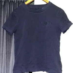 Mörkblå t-shirt från GANT - Snygg mörkblå t-shirt från GANT med broderad logga på bröstet. Perfekt för en casual look. Använd max 5 gånger och inga defekter förekommer💕