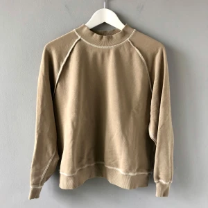 Beige tröja från H&M Sport - Säljer en beige tröja från H&M Sport. Tröjan har långa ärmar och är tillverkad i bomull med ribbade muddar vid ärmslut och nederkant. I bra skick och knappt använd.