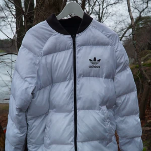 Vit och svart dunjacka från Adidas - ❤️Säljer en snygg reversible dunjacka från Adidas originals❤️Jackan har en klassisk Adidas-logga på bröstet och är perfekt för kyligare dagar. Väldigt bra skick🌟🌟Storlek S men passar även M📏🕺🏻Använt endast ett par gånger