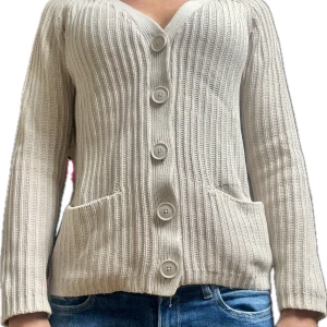 Beige ribbad kofta med knappar - Säljer en snygg beige ribbad kofta med stora knappar framtill. Koftan har långa ärmar och praktiska fickor. Perfekt för en stilren och bekväm look. Passar till både jeans och kjol!