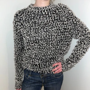 Svartvit stickad tröja från Samsøe Samsøe - Säljer en mysig svartvit stickad tröja från Samsøe Samsøe. Tröjan har en grovstickad textur och långa ärmar, perfekt för kyliga dagar. Den har en rund halsringning och en avslappnad passform.