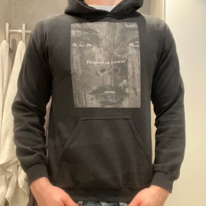 Svart hoodie med tryck - Säljer en svart hoodie med ett stort tryck på framsidan. Hoddien är från emplace och är i storlek S. Hör av dig vid nånon fråga🌟