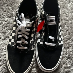 Svartvita rutiga sneakers från Vans - Snygga svartvita sneakers från Vans med klassiskt rutigt mönster. Skorna har vit snörning och en brun sula med bra grepp. Oanvända storlek 45