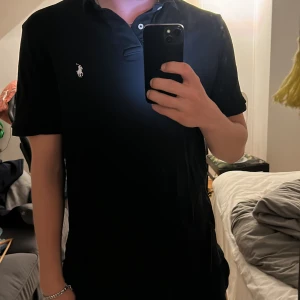 Svart pikétröja från Polo Ralph Lauren - Svart pikétröja från Polo Ralph Lauren i storlek M säljer då den är för liten bra skick och väl omhändertagen hör av dig om de är några funderingar. Kan gå ner i pris vid snabb affär.