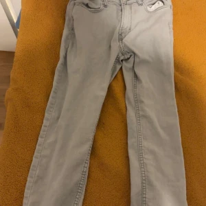 Ljusgrå raka jeans - Säljer ett par ljusgrå jeans med klassisk femficksdesign och raka ben. Jeansen har normal passform och är tillverkade i mjukt bomullstyg. Perfekta för en clean och avslappnad stil.