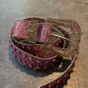 Glittrigt rosa bälte med nitar - Bälte i rosa med glittrig yta och massor av rosa stenar. 